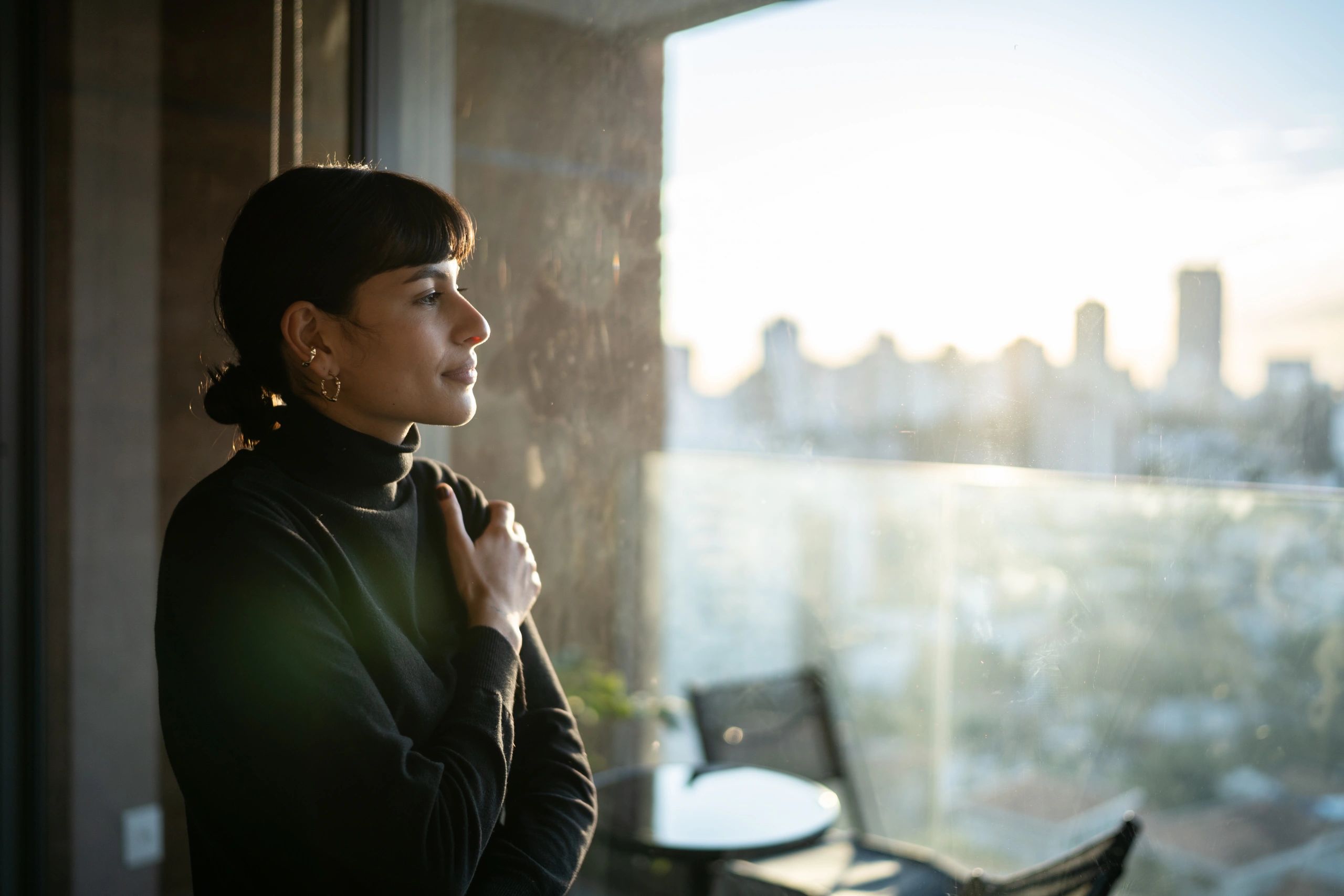 Woman reflecting by a window in soft evening light