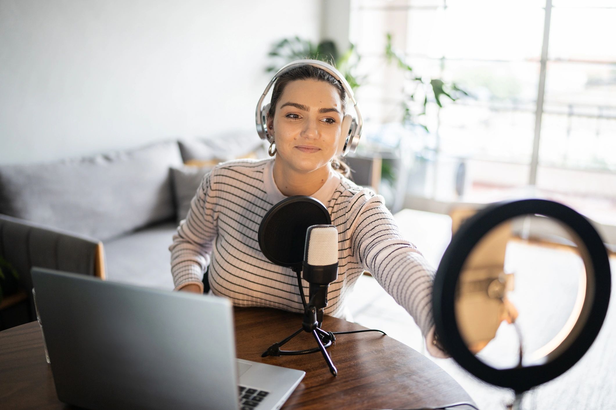 Woman recording a podcast at home with headphones
