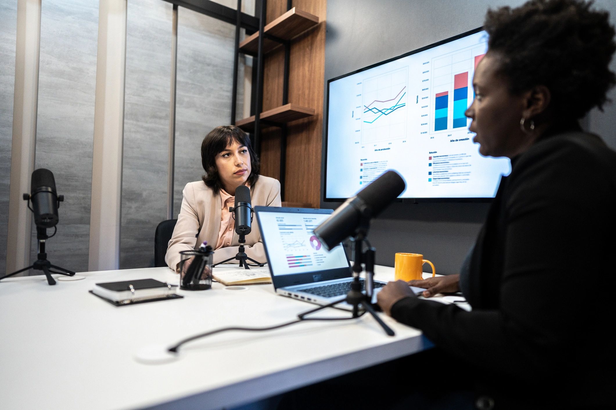 Two women recording a podcast together with microphones and headphones